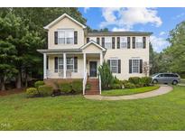 Charming two-story home with a well-manicured lawn and a welcoming front porch and black shutters at 136 Garden Retreat Dr, Garner, NC 27529