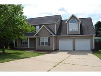 Charming two-story home with a two car garage and manicured lawn and a mature tree at 136 Wedgewood Ct, Sanford, NC 27332