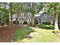 Two-story home with gray siding, white shutters, brick walkway, and well-maintained landscaping in a wooded area at 2708 Coleberry Trl, Rocky Mount, NC 27804