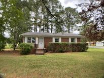 Charming single-story brick home with a well-manicured lawn and mature trees providing shade at 2915 Ross Rd, Durham, NC 27703