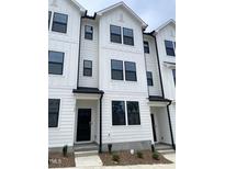 A bright exterior view of newly constructed townhomes with black trim and white siding at 3105 White Blossom Ct, Raleigh, NC 27610
