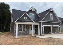 Charming home featuring a two-car garage, stone accents, gabled roof, and a welcoming front porch at 318 Abingdon Farms Dr, Selma, NC 27576