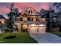 Inviting two-story home with a stone and siding facade, covered porch, and well-manicured lawn at twilight at 4104 Green Chase Way, Apex, NC 27539