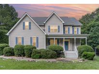 Charming two-story home with a cozy front porch, blue shutters, and meticulously landscaped front yard at 457 Poplar Forest Ln, Pittsboro, NC 27312