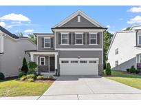 Charming two-story home boasts a manicured lawn, gray siding, shutters, and a two-car garage at 4940 Enlightenment Rd, Raleigh, NC 27616