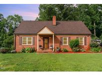 Charming brick home featuring a cozy front porch and beautifully manicured lawn at 132 Lord Ashley Rd, Raleigh, NC 27610