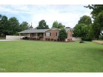 Charming brick ranch-style home with mature trees, lush green lawn, and convenient carport at 1418 Sherron Rd, Durham, NC 27703