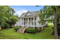 Stately two-story home with white siding, a metal roof, and a welcoming front porch with grand columns at 4053 Friendship Patterson Mill Road, Burlington, NC 27215