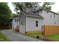 View of a light gray two-story home with an attached garage and a stone driveway at 4511 Denfield St, Durham, NC 27704