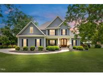 Charming two-story home featuring gray siding, black shutters, manicured landscaping, and a welcoming front porch at 532 Joe Collins Rd, Lillington, NC 27546