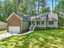 Charming single-Gathering home boasts stone accents, a manicured lawn, and an attached two-car garage at 6102 Burning Tree Cir, Sanford, NC 27332