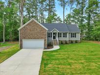 Charming single-story home featuring a stone facade, attached garage, and well-manicured lawn at 6102 Burning Tree Cir, Sanford, NC 27332
