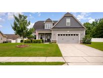 Charming home featuring a well-manicured lawn, a two-car garage, and a welcoming front porch area at 71 Sanibel St, Clayton, NC 27520