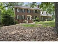 Charming two-story brick home featuring a well-manicured lawn and mature trees at 821 Ascot Ln, Raleigh, NC 27615