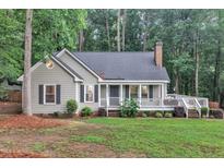 Charming single-story home featuring a cozy front porch, landscaped yard, and classic architectural details at 8801 Valley Hill Ct, Apex, NC 27539