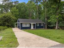 Charming blue single-story home featuring a long driveway, lush lawn, and surrounded by mature trees at 105 Hanna St, Carrboro, NC 27510