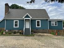 Charming blue house with white trim, brick foundation and chimney, and a gravel driveway at 3129 Skycrest Dr, Raleigh, NC 27604