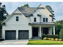 Attractive two-story home with white siding, gray trim, large windows, and two-car garage at 6900 Staghorn Ln, Raleigh, NC 27615