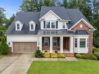 Charming two-story home featuring a blend of brick and white siding, a well-manicured lawn, and an attached two-car garage at 7502 Latteri Ct, Raleigh, NC 27613