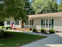 Charming one-story home with green shutters and manicured front yard with a North Carolina state flag at 835 Pearleman Teague Rd, Siler City, NC 27344