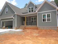 Charming new construction home featuring gray siding, brick accents, and an attached two-car garage at 1155 Shonele Ln, Stem, NC 27581