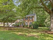 Charming brick home with lush landscaping and a welcoming front porch, perfect for enjoying the outdoors at 128 Castlewood Dr, Cary, NC 27511