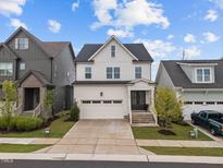 Charming two-story home with white siding, attached garage, and beautifully landscaped front yard at 140 Big Barn Dr, Wendell, NC 27591