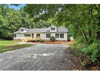 Charming single-story home featuring a front deck and a gravel driveway nestled among lush trees at 160 Deer Tracks Dr, Wendell, NC 27591