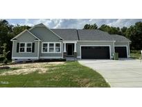 Charming single-story home with sage green siding, black garage doors, and manicured lawn at 176 Bonsai Way, Four Oaks, NC 27524