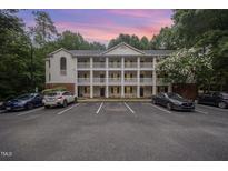 Three-story condo complex with white siding, black doors, and private balconies overlooking the parking area at 1851 Trailwood Heights Ln # 204, Raleigh, NC 27603