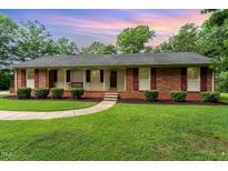 Charming single-story brick home featuring a well-manicured lawn and lovely front porch at 2139 Race Track Rd, Burlington, NC 27215