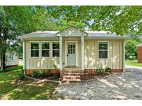 Charming single-story home featuring a quaint entrance, metal roof, and a well-maintained landscaped front yard at 502 S Eighth St, Mebane, NC 27302