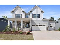 Beautiful two-story home with a stone-accented porch and a two-car garage, complemented by manicured landscaping at 713 Ramsours Mill Dr, Holly Springs, NC 27540
