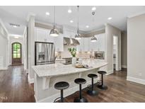 Bright kitchen features a large island with seating, stainless steel appliances and modern pendant lighting at 728 Peninsula Forest Pl, Cary, NC 27519
