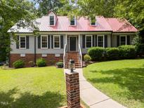 Charming home with red metal roof, black shutters, manicured lawn, and inviting walkway at 101 Joel Ct, Cary, NC 27513