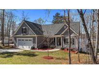Charming gray home boasts a manicured lawn, an attached two-car garage, and a quaint front porch at 1013 Sagamore Dr, Louisburg, NC 27549
