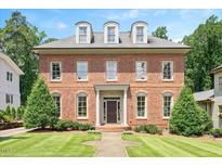 Stately two-story brick home featuring a manicured lawn and symmetrical landscaping at 1313 Duplin Rd, Raleigh, NC 27607