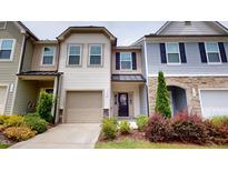 Charming townhouse with beige siding, front garden, and attached one-car garage with concrete driveway at 1365 Scholar Dr, Durham, NC 27703