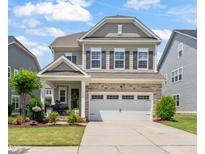 Charming two-story home with stone accents, a well-manicured lawn, and a two car garage at 212 Golf Vista Trl, Holly Springs, NC 27540