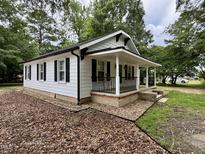 Charming single-story home features a covered front porch, white siding, and black shutters at 306 Penny St, Garner, NC 27529
