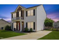 Charming two-story home features a red door, brick accents, a small balcony, and a well-maintained lawn at 3101 Riverbrooke Dr, Raleigh, NC 27610