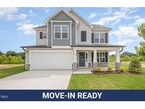 Charming two-story home with a light gray and blue exterior and a well-manicured front lawn at 44 Chloe Ct, Selma, NC 27576