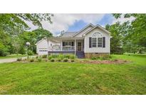 Charming home with a well-manicured lawn, lovely landscaping, and a welcoming front porch at 5309 Meadow Field Dr, Mebane, NC 27302