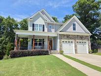 Charming two-story home featuring a stone facade, inviting front porch, and manicured lawn at 604 Doddington Dr, Rolesville, NC 27571