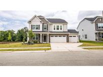 Charming two-story home with stone accents, a three-car garage, and a well-manicured lawn at 1051 Jura Ridge Dr, Fuquay Varina, NC 27526