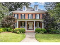 Charming brick home featuring a manicured lawn, inviting front porch with rocking chairs, and classic architectural details at 1414 Park Dr, Raleigh, NC 27605