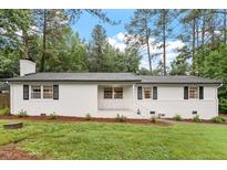 Charming single-story home with a white painted brick exterior, black shutters and a well-manicured lawn at 1523 Oak Forest Dr, Hillsborough, NC 27278