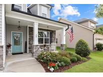 Charming covered front porch with stone accents, rocking chairs, and a beautifully landscaped garden at 20 Sweet Birch Row, Youngsville, NC 27596