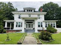 Charming two-story home with a well-maintained lawn and beautiful white exterior at 275 Gholson Ave, Henderson, NC 27536