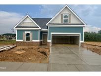 New construction home featuring teal siding, brick accents and two car garage with newly poured concrete driveway at 360 Ambassador Dr, Clayton, NC 27520